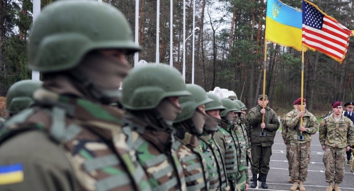 Ветерани стоять біля прапора України та США — символ двох моделей ставлення до захисників